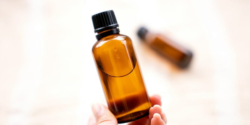 a person holding a bottle of essential oils